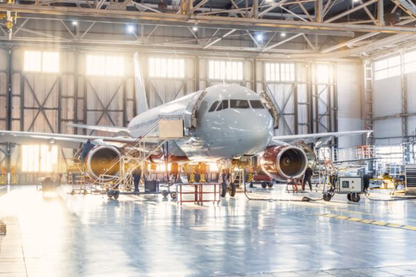 A large airplane in an airport hangar with people around.