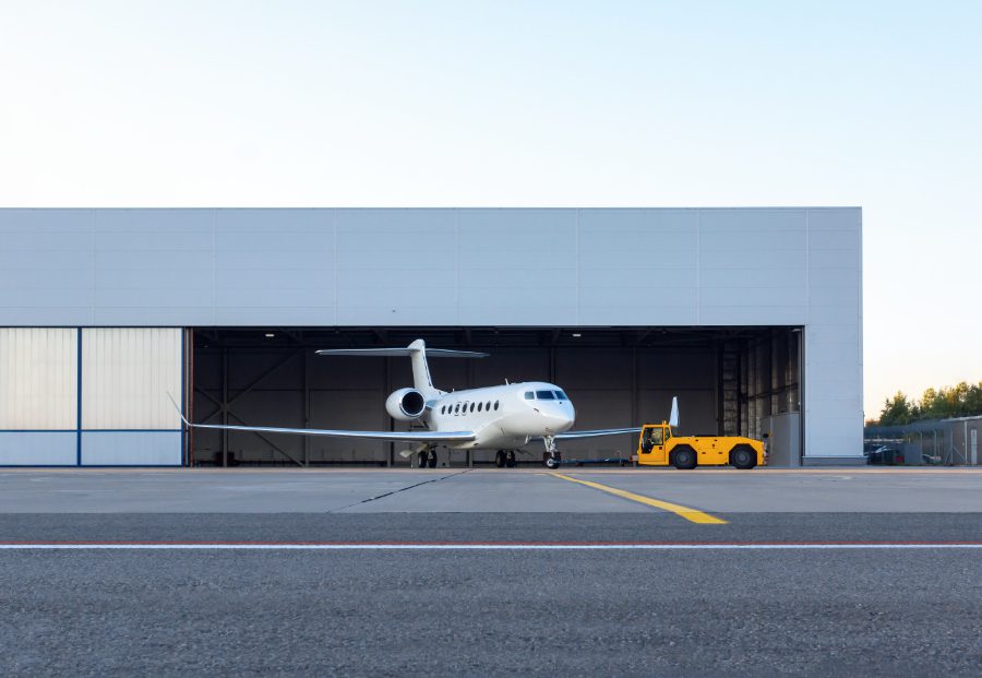 A plane is parked in front of a hangar.