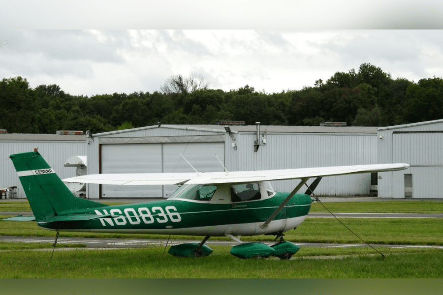 A small green and white plane sitting on top of grass.