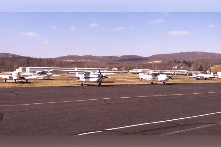 A group of small airplanes parked on the runway.