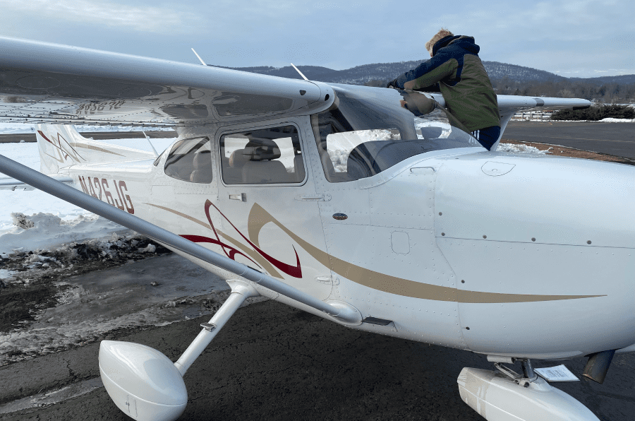 nh2 A man standing on the wing of an airplane.