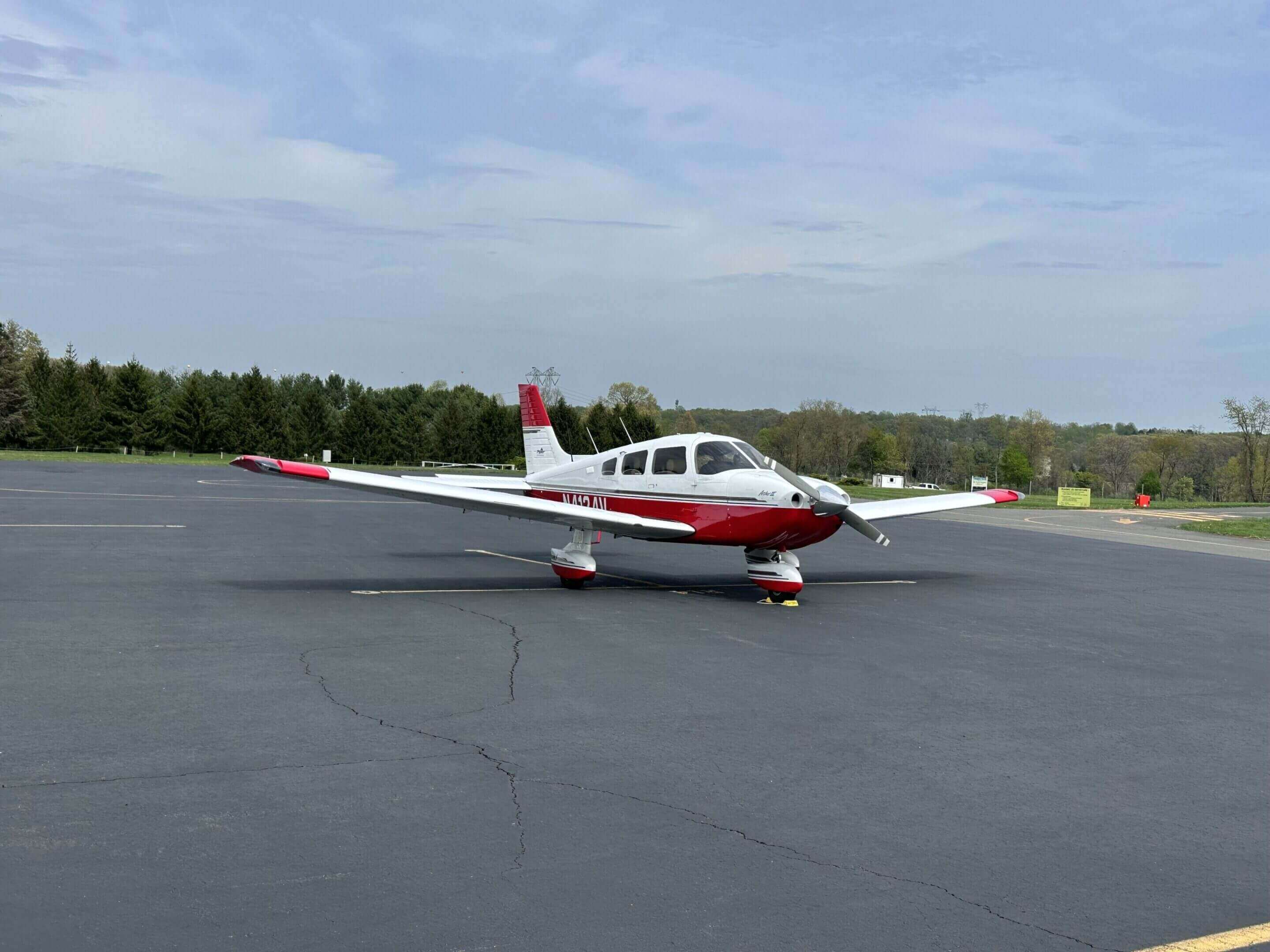 Small red and white airplane on tarmac.