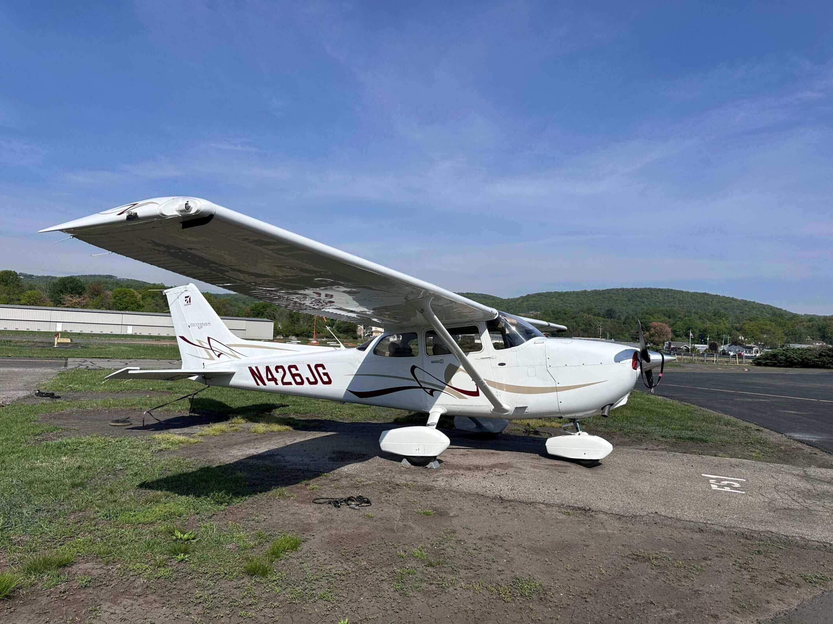 Small airplane parked on grassy runway.