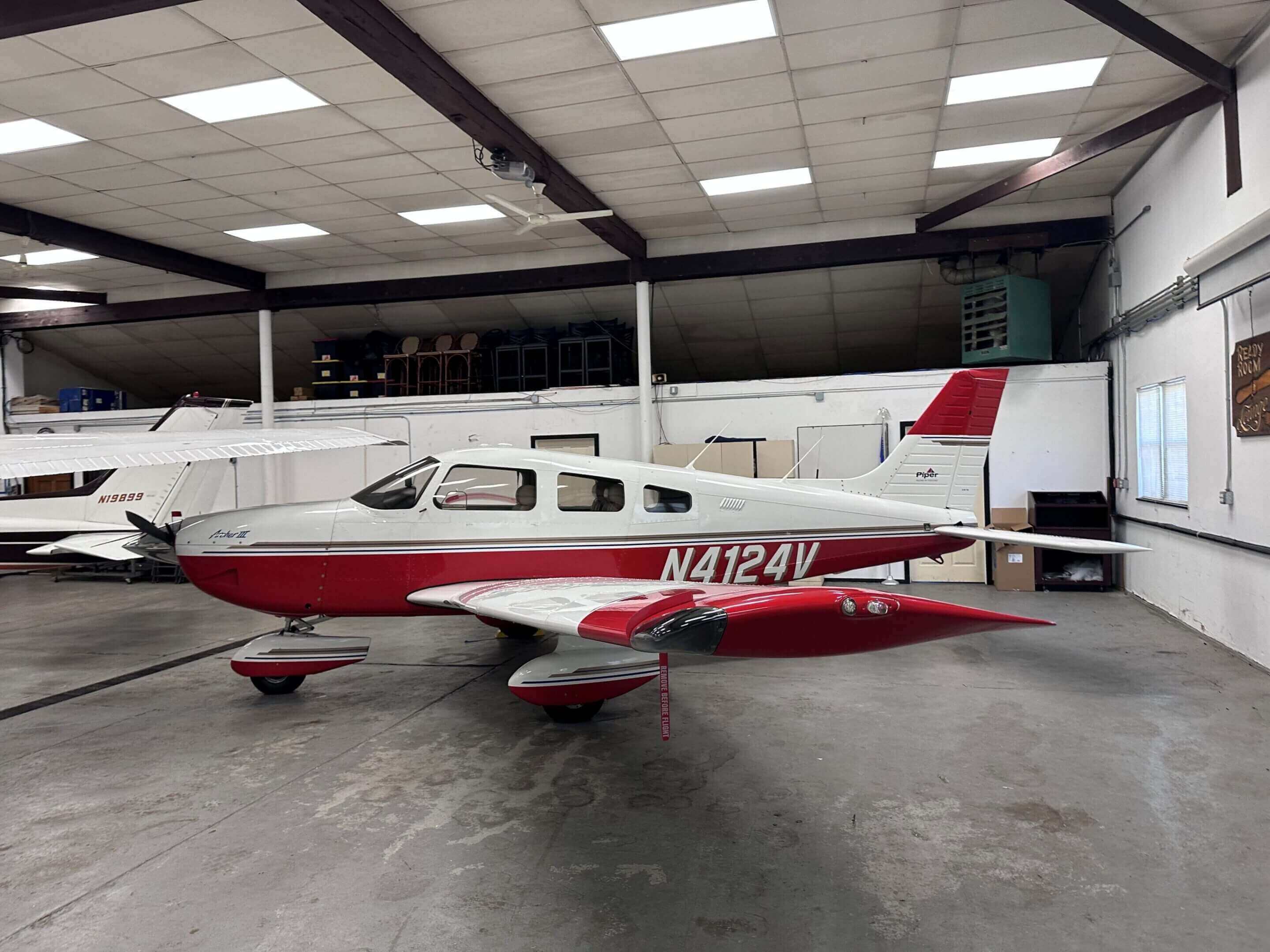 Red and white airplane inside a hangar.