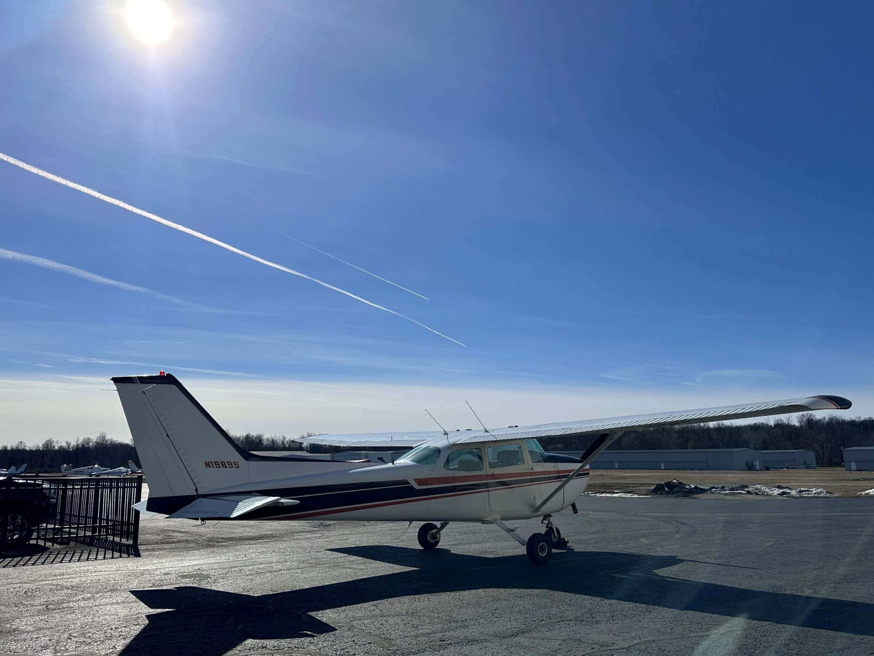 Small airplane parked on sunny tarmac.