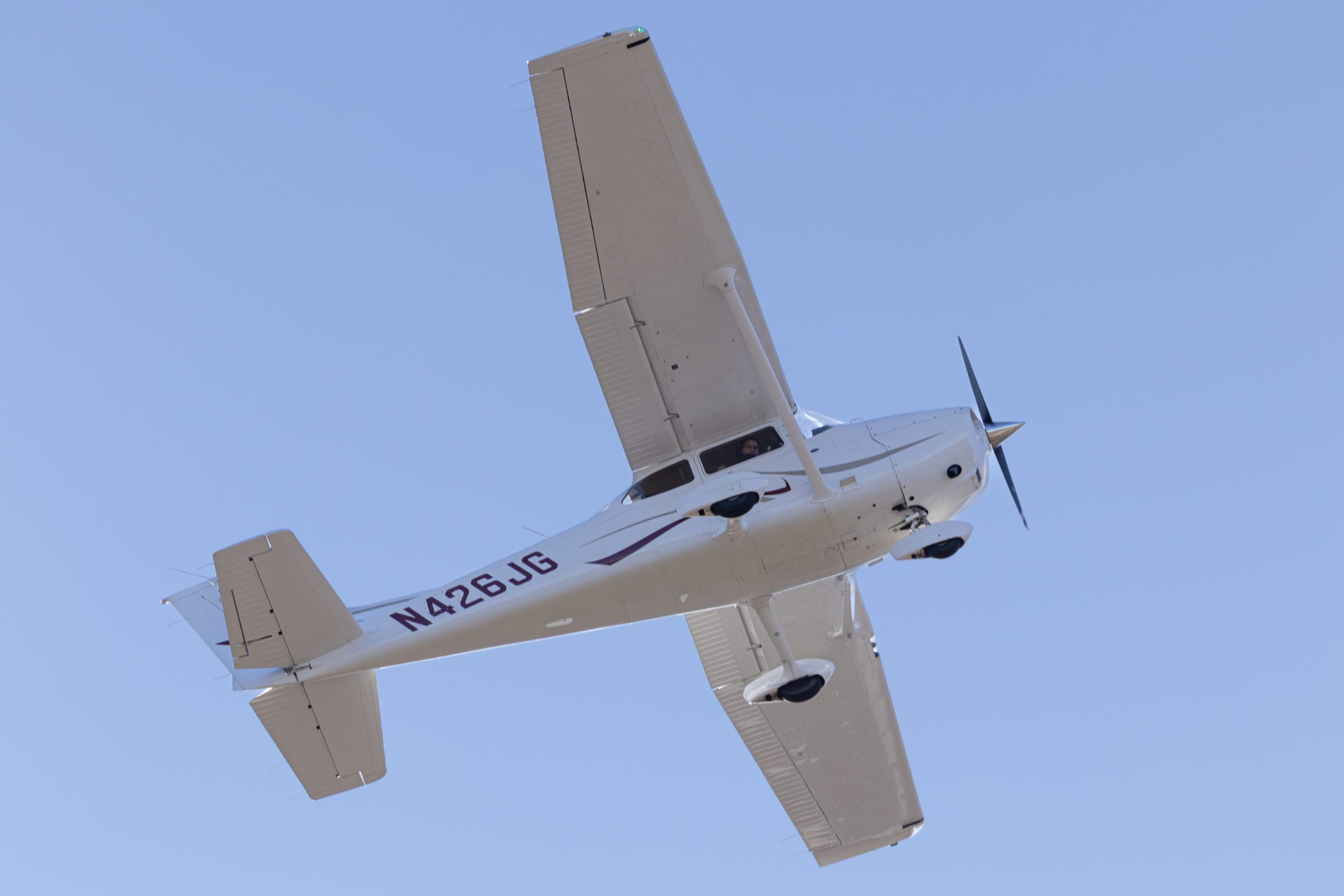 Small airplane flying in clear blue sky.