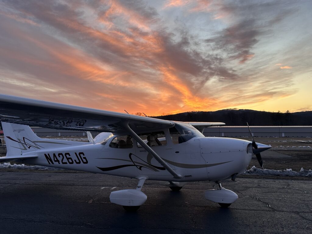Small airplane on runway at sunset sky.
