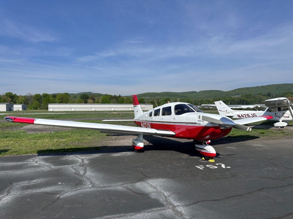 Red and white small airplane on tarmac.