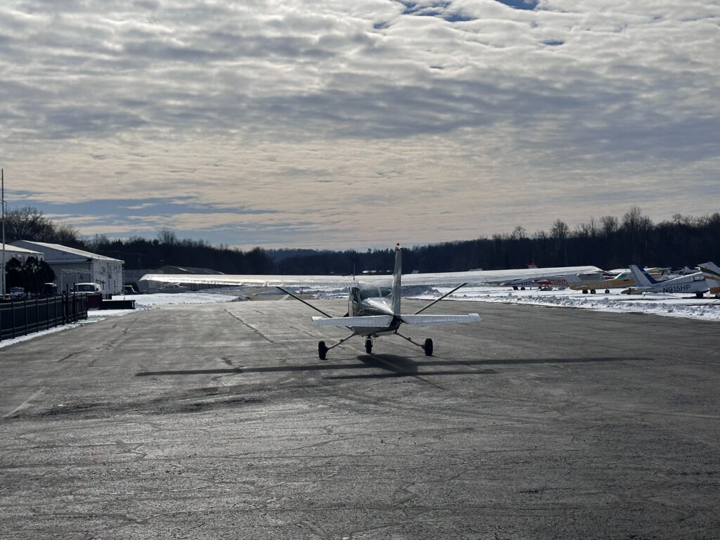 Small airplane on snowy runway under cloudy sky.