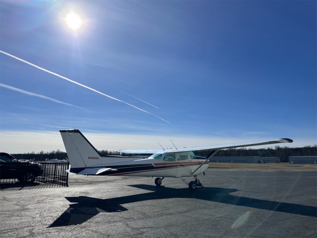 Small airplane parked on sunny tarmac.