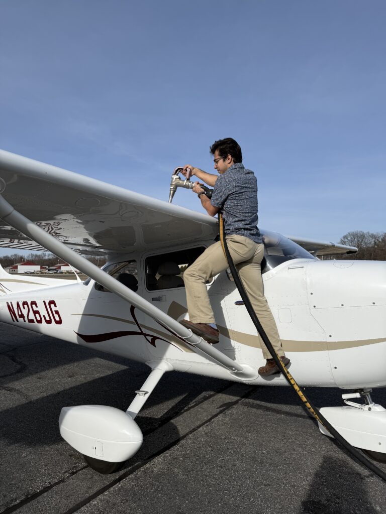 Man refueling small airplane on tarmac.