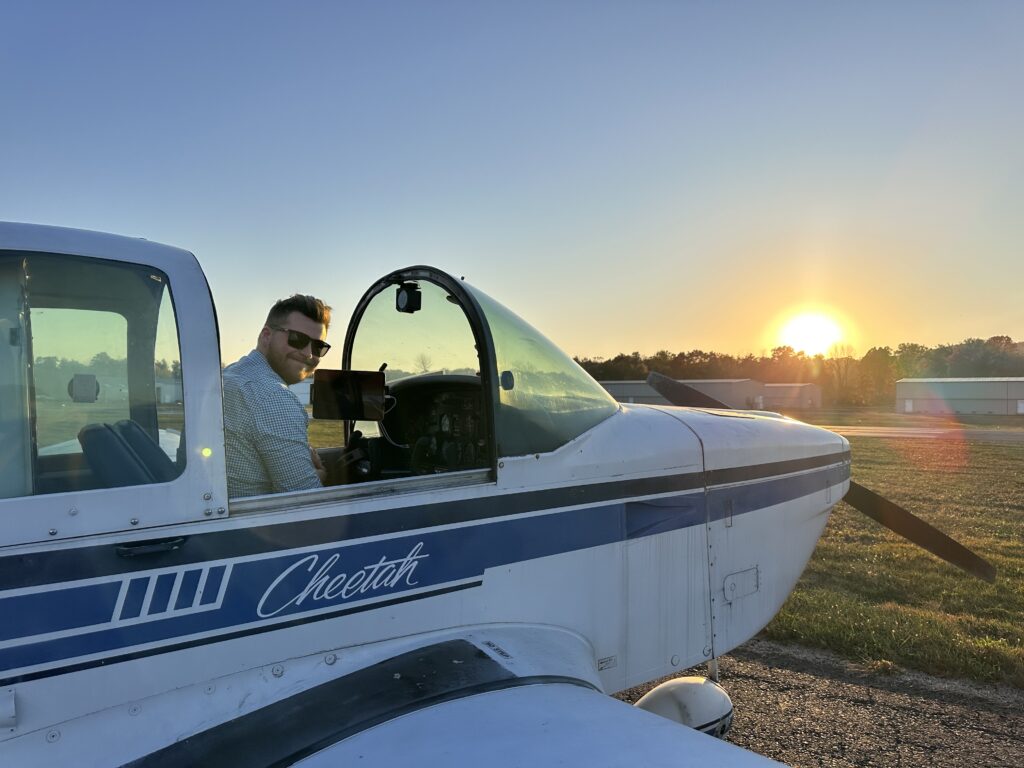 Man in small plane at sunset.