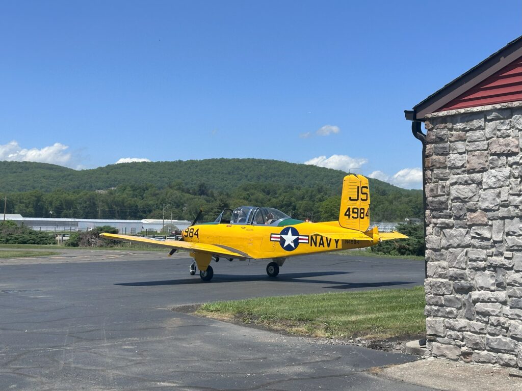 Yellow vintage Navy airplane on tarmac.