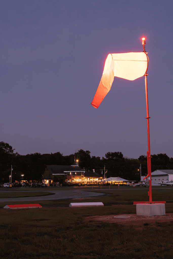 Illuminated windsock at dusk near building.
