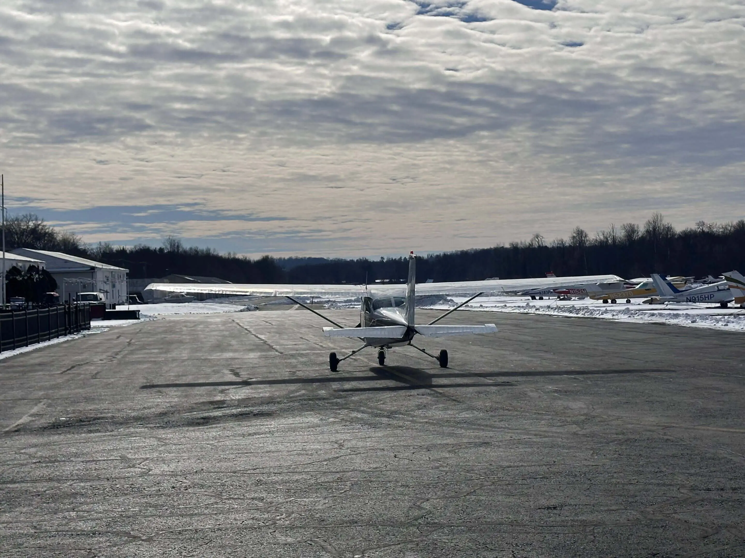 Small airplane on snowy runway under cloudy sky.