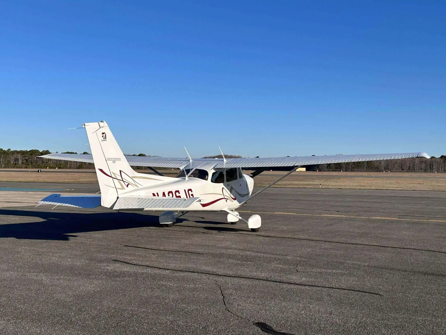 Small airplane parked on runway, clear sky.